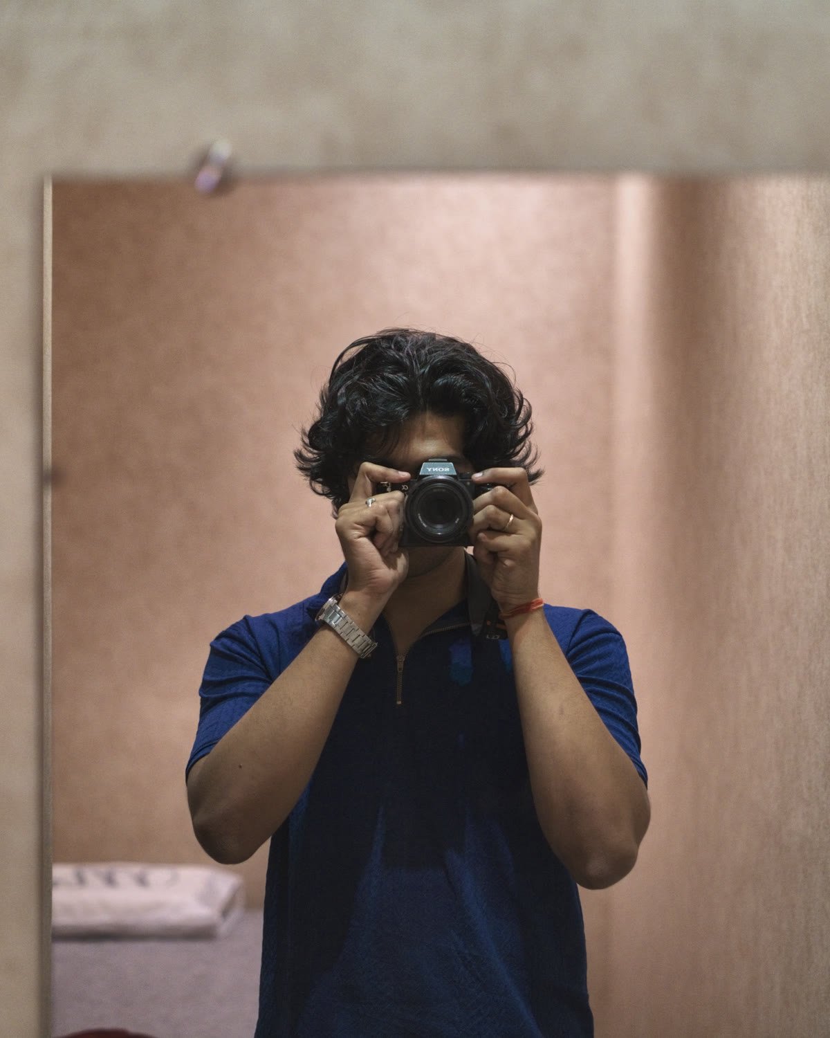 Vignesh photographed in a mirror, holding a camera to his face.